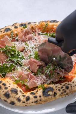 Prosciutto, roka ve parmesanlı pizza.