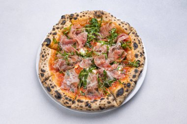 Prosciutto, roka ve parmesanlı pizza.
