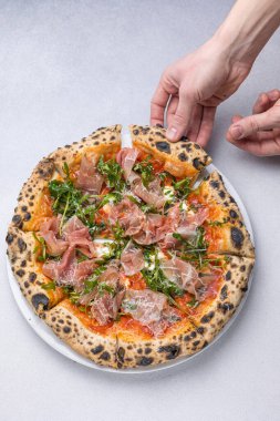 Prosciutto, roka ve parmesanlı pizza.