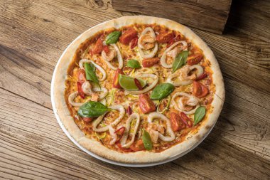 Kaba ahşap arka planda deniz mahsullü pizza.