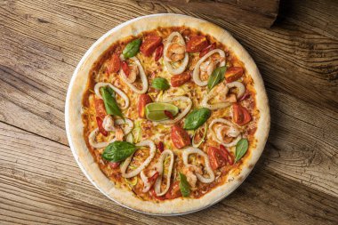 Kaba ahşap arka planda deniz mahsullü pizza.