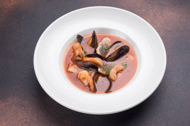 Somon balıklı deniz ürünleri çorbası ve tabakta midye.