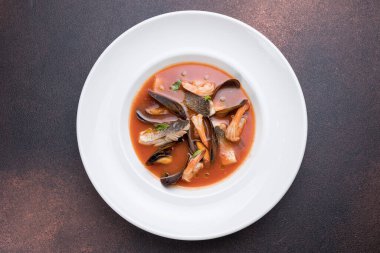 Somon balıklı deniz ürünleri çorbası ve tabakta midye.