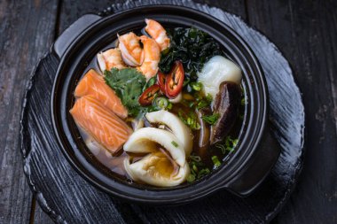 Somon balıklı deniz ürünleri çorbası ve tabakta midye.