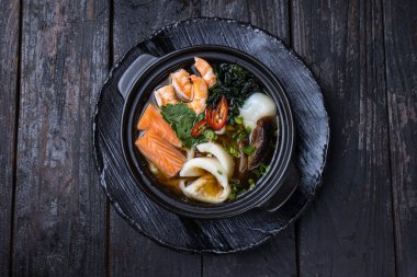 Somon balıklı deniz ürünleri çorbası ve tabakta midye.