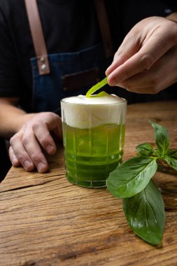 Tahta bir masada fesleğenli yeşil alkollü kokteyl..