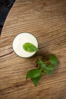 Tahta bir masada fesleğenli yeşil alkollü kokteyl..