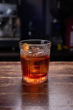 Portakallı kokteyl ve ahşap bir masada buzlu bardak.