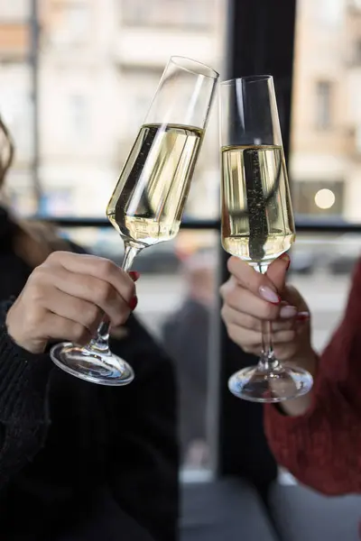 レストランでシャンパンで乾杯する2人の女性の手のクローズアップ ロイヤリティフリーのストック写真