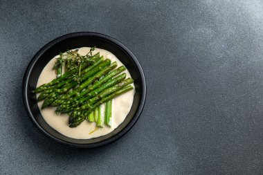 Siyah bir kasede siyah bir arka planda kremalı kuşkonmaz.