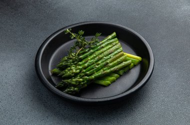 Siyah bir kasede siyah bir arka planda kremalı kuşkonmaz.