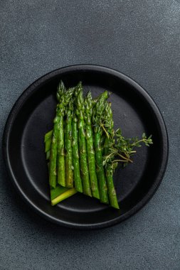 Siyah bir kasede siyah bir arka planda kremalı kuşkonmaz.