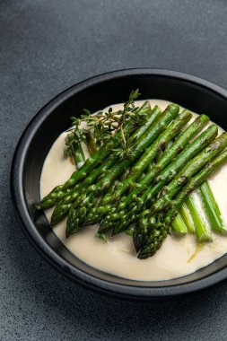 Siyah bir kasede siyah bir arka planda kremalı kuşkonmaz.