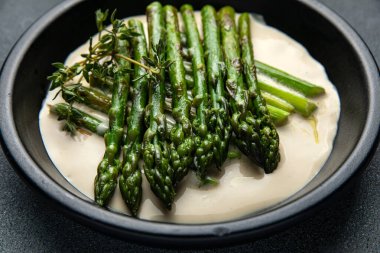 Siyah bir kasede siyah bir arka planda kremalı kuşkonmaz.