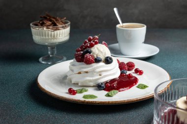 Çilekli Pavlova ve beyaz tabakta krem şanti.