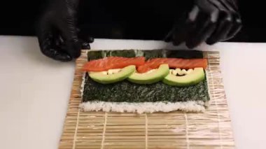 Şef lezzetli somon ruloları pişiriyor. Japon mutfağı.
