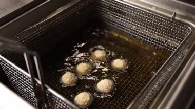 Mutfakta, fritözde köfteler kızarır. Yakın plan.