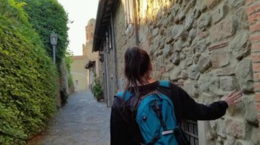 Eski Castiglione della Pescaia şehrinin sokaklarında yürüyen bir turist kız.