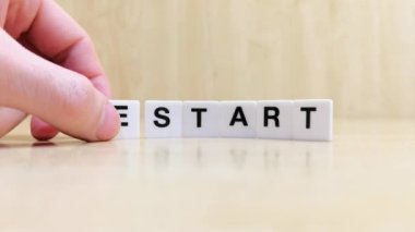 Kelimeyi dönüştüren bir el üzerinde harfler yazılı beyaz kiremitleri yeniden kullanmaya başla.