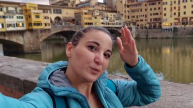 Floransa 'daki ünlü Ponte Vecchio' nun özgeçmişi ile özçekim yapan gülümseyen bir turist kız.