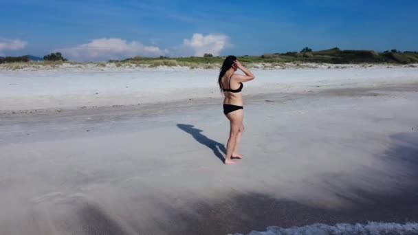 一个穿着泳衣的女孩在海滨散步 从后面可以看到植物 — 图库视频影像