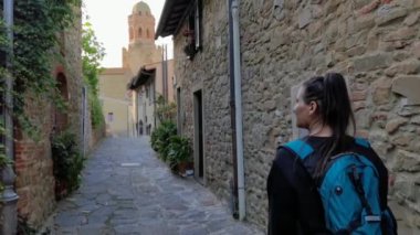 Castiglione della Pescaia İtalya, Haziran 05, 2023: Eski şehir duvarlarıyla sokakta yürürken gülümseyen bir kız