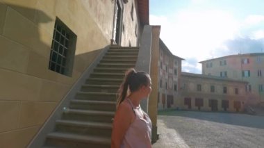San Miniato İtalya, 15 Haziran 2023: Bir kız piskoposluk okulunun merdivenlerinden aşağı inerken kendini meydanda etrafına bakarken buluyor.