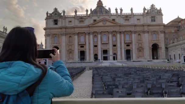 ローマの観光ツアーに参加している女性がバチカン市のセントピーターズバシリカの正面写真を撮っています — ストック動画