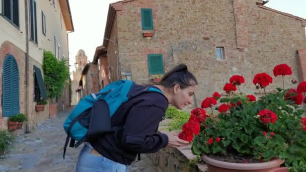 イタリアのカスティグリオーネ デッラ ペッスカイア 2023年6月05日 街路を歩いている少女が赤い花の匂いを止める — ストック動画