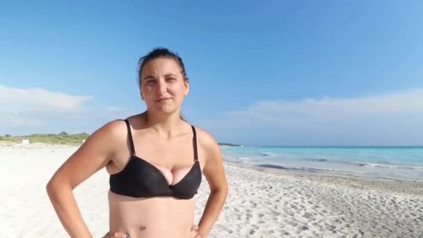 수영복에있는 소녀는 해변에있는 누군가에 그녀의 얼굴에 그녀의 머리의 흔적과 그림자를주지 — 비디오