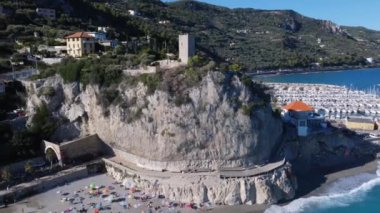 Finale Ligure denizine tepeden bakan kayalık dağdaki antik bir kulenin panoramik hava görüntüsü