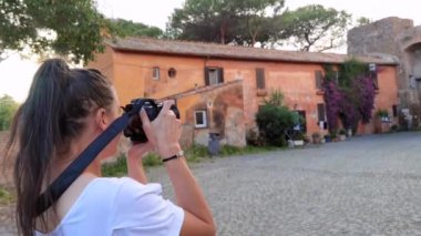Ostia Antica İtalya, 29 Mayıs 2023: Ortaçağ köyü ve renkli çiçekli evleri fotoğraflayan bir turist kız