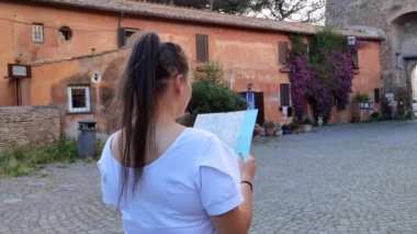 Ostia Antica 'nın ortaçağ köyünde coğrafi haritası olan bir turist kız.