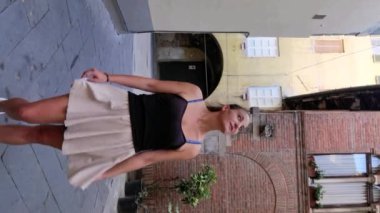 Lucca 'nın merkezinde arka planda antik binalar olan bir kızın dikey görüntüsü.