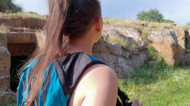 Egy Kék Hátizsákos Lány Sétál Etruszk Temető Zöldjében Körülnéz — Stock videók