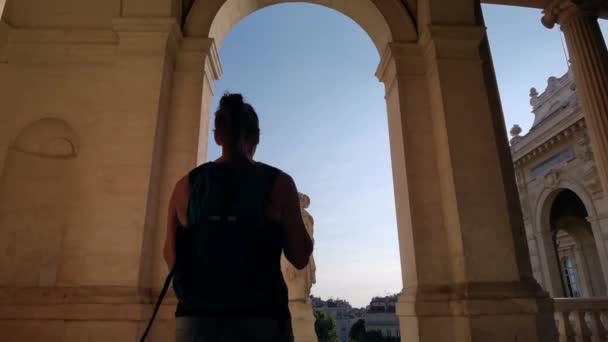 ロングチャンプ宮殿のアーチの間を歩く観光ガールは 構造から出てくる — ストック動画