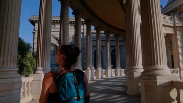 Τουριστικό Κορίτσι Περπάτημα Μεταξύ Των Στηλών Του Longchamp Palace Κοιτάζοντας — Αρχείο Βίντεο