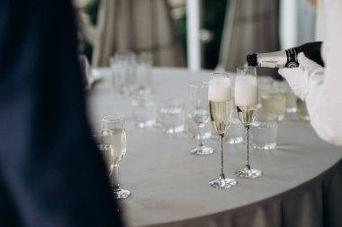 waiter pouring wine into a glass with a bottle of champagne