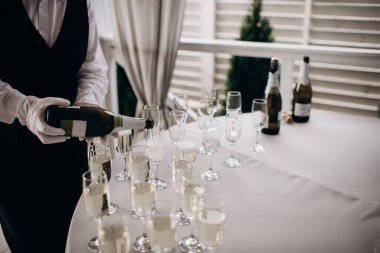 waiter pouring wine into a glass with a bottle of champagne