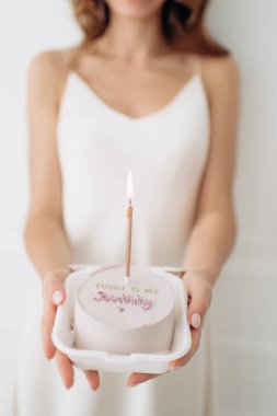 a small cake with burning candles in honor of the birthday of a young beautiful girl