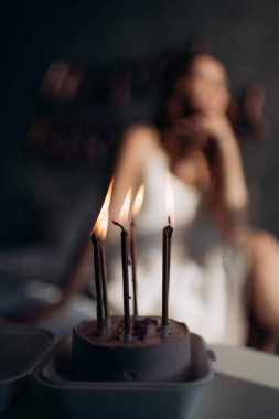 a small cake with burning candles in honor of the birthday of a young beautiful girl