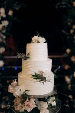 beautiful wedding cake with white roses in the background on a blurred of a restaurant
