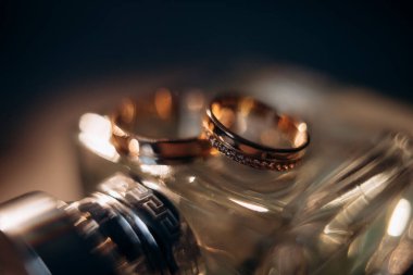 wedding rings on against the backdrop of a bottle of perfume