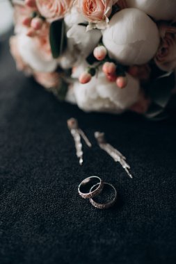 Gelin çiçeğinin arka planında alyanslar var.