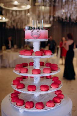 kırmızı doğum günü pastası katlı tezgahta küçük keklerle