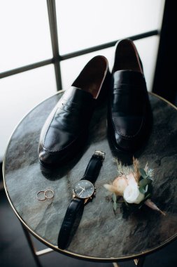 Bir çift ayakkabı ve masanın üzerinde bir saat.