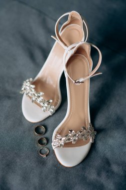 Gelinin pırıl pırıl nişan yüzüğü, şık topuklular. Gelinin düğün ayrıntıları ve aksesuarları..