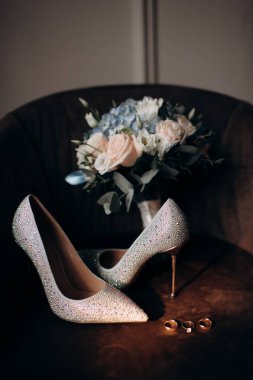 Gelinin kıyafetlerinin ayrıntıları, şık düğün aksesuarlarının modern bir kompozisyonu, yüksek topuklu ayakkabılar, altın alyanslar. Düğün hazırlıkları.