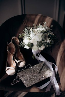 Gelinin kıyafetinin detaylarının yakın plan çekimi modern bir düğün aksesuarı, yüksek topuklu ayakkabılar, modern bir gelin buketi. Düğün hazırlıkları.