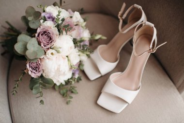 Gelinin kıyafetinin detaylarının yakın plan çekimi modern bir düğün aksesuarı, yüksek topuklu ayakkabılar, modern bir gelin buketi. Düğün hazırlıkları.